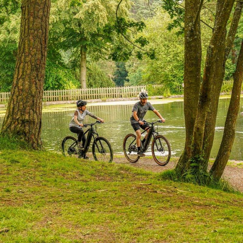 Claud_Butler_Wrath_1.0_lifestyle two people riding down a path by a pond in a park