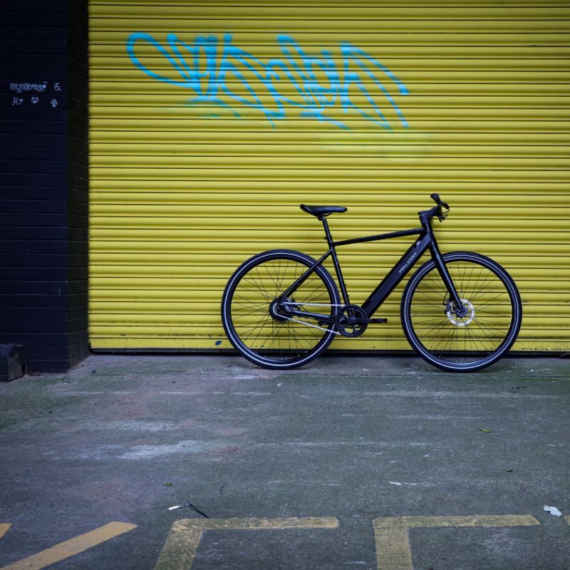 Falcon Zone Hybrid e-bike lifestyle town parked in front of a yellow garage door with graffiti