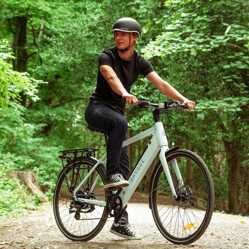 Person riding a Hygge Losso white electric bike in a forested area