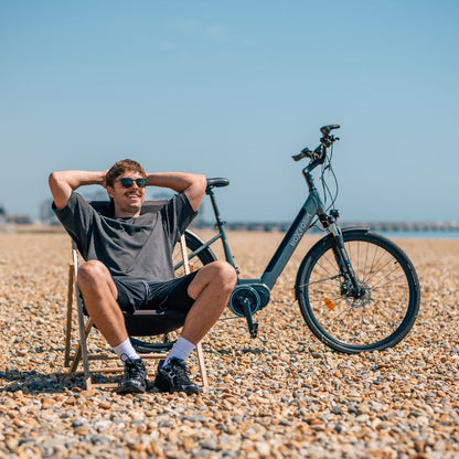Roxform_Stride_L_e-bike lifestyle beach Man sitting on a folding chair on a pebbly beach.