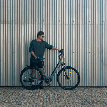 Roxform_Stride_L_e-bike lifestyle city Man holding the bicycle against a corrugated metal wall