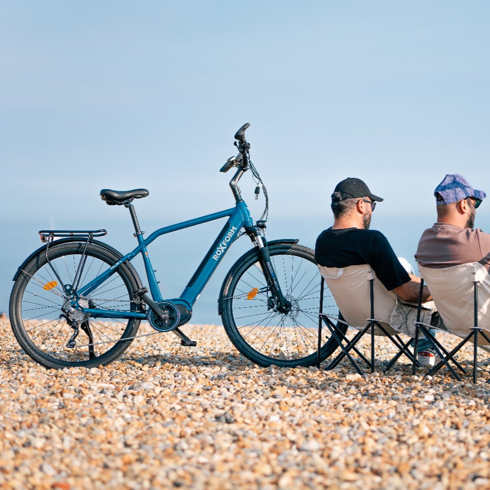 Roxform Valor L e-bike Two people sitting on chairs on a pebbly beach.