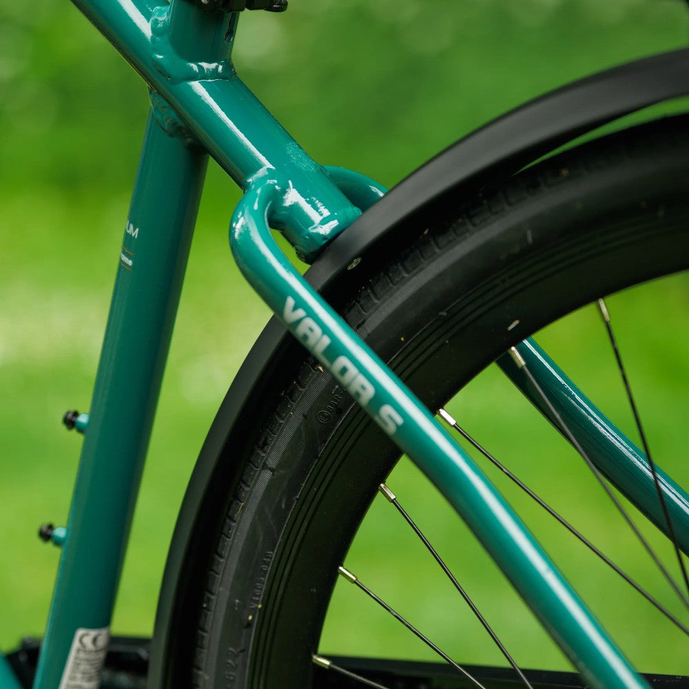 Close-up of a teal bicycle frame with 'Valor S' branding against a green background