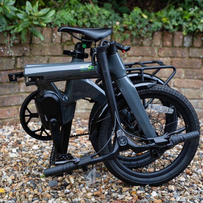 e-go CarbonLite3S folded on a gravel surface with a brick wall and greenery in the background