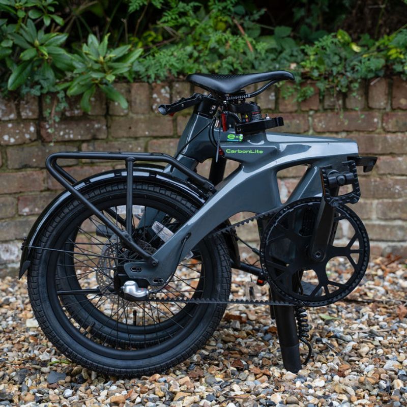 e-go CarbonLite3S folded with seat post in place on a gravel surface with a brick wall and greenery in the background